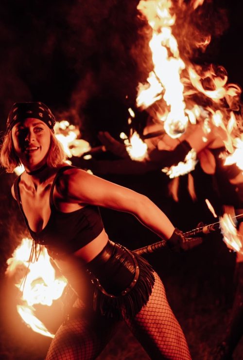 Woman performs with fire staff.
